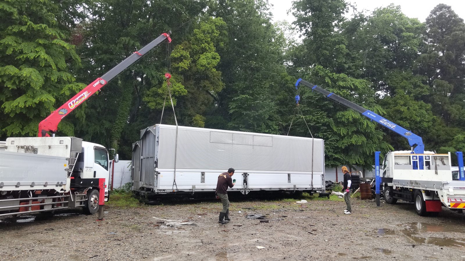 Truck cranes lifting a cargo body during preparation in Japan